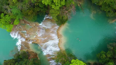 Aerial-top-down-shot-of-people-swimming-in-rocky-waterfall-pools,-tropical-scene