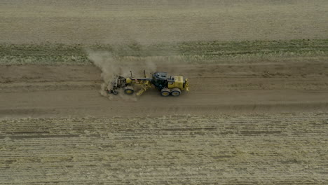 Aerial-Side-View,-Tractor-Road-Grader-Flattening-Field-Surface-For-New-Road,-Saskatchewan,-Canada
