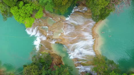 Aerial:-travellers-swimming-in-tropical-waterfall-pools,-rising-top-down-view
