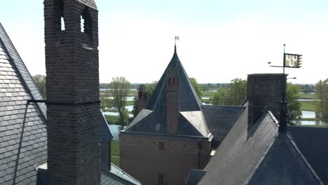 Drohne,-Die-Zwischen-Dächern-Von-Schloss-Loevestein-Fliegt,-Endet-In-Einer-Weiten-Aufnahme-Des-Denkmals-An-Einem-Hellen-Sonnigen-Tag-In-Holland