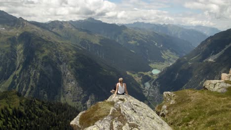 Mujer-Joven-Sentada-En-Un-Acantilado-En-La-Cima-De-Una-Montaña-Y-Disfrutando-De-La-Increíble-Vista-De-La-Montaña-En-Los-Alpes-Tiroleses