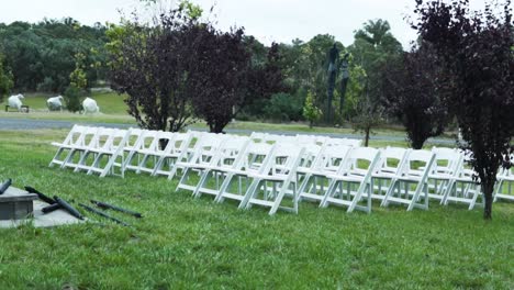 White-Folding-Chairs-At-An-Outdoor-Wedding-On-A-Green-Meadow---wide-shot