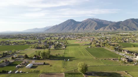 AERIAL---The-Wasatch-Mountains-and-farmland-in-Mapleton,-Utah,-wide-shot