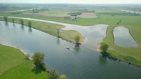 Aerial-drone-view-of-flying-over-the-lake-and-revealing-a-boat-is-passing-by-in-the-Netherlands