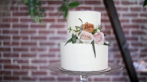 Elegant-Two-Tiered-White-Wedding-Cake-On-Glass-Stand-With-Floral-Decor