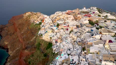 drone-video-of-famous-white-and-colourful-picturesque-village-of-Oia-built-on-a-cliff-at-sunset,-Santorini-island,-Cyclades,-Greece