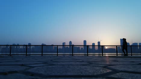 Zeitlupen-silhouette:-Eine-Frau,-Die-Während-Des-Sonnenaufgangs-In-Sharjah,-Vereinigte-Arabische-Emirate,-Mit-Einer-Skyline-Der-Stadt-Im-Hintergrund-Trainiert