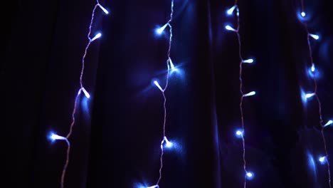 Blue-Colored-Fairy-String-Lights-Glitter-On-The-Wall-At-Dark