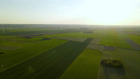 Atemberaubende-Luftaufnahme-Von-Windkraftanlagen-Auf-Den-Grünen-Landwirtschaftlichen-Ebenen-Feldern-Bei-Sonnenuntergang-In-Puck-Polen