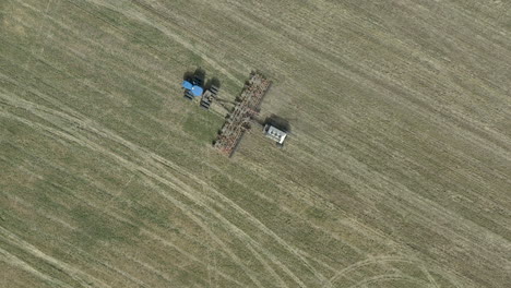 Tractor-pulling-seeding-machine-on-open-field-in-Canada,-aerial