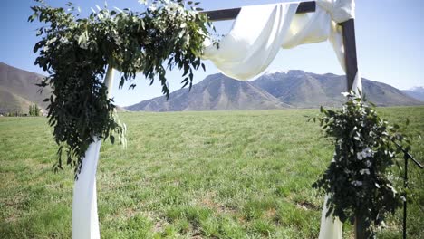 Wedding-Arch-With-White-Cloth-And-Flowers-For-An-Outdoor-Wedding-Ceremony-In-The-Meadow---wide-shot