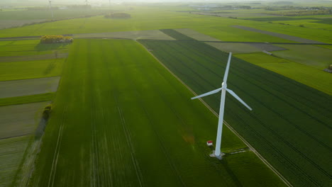 Beautiful-aerial-orbit-around-wind-power-turbine-in-green-rural-fields-environment
