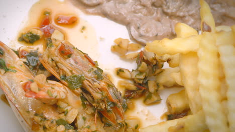 Meat-in-sauce,-prawns,-steamed-vegetables-and-French-fries,-close-up,-Mediterranean