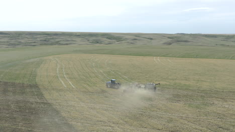 Tractor-seeding-in-huge-field-in-Canada,-tracking-aerial-drone-shot
