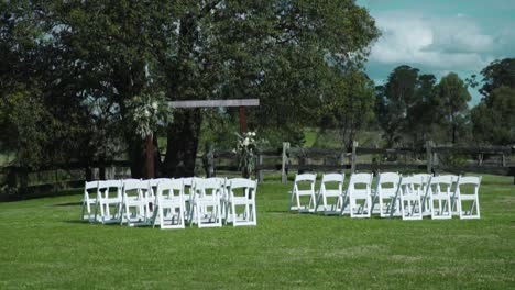 Rows-Of-Guest-Chairs-Arranging-On-A-Lawn-With-Lush-Trees-In-Background-During-Outdoor-Wedding