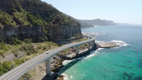 Cliff-Edge-Road-With-Traveling-Cars-On-Summertime-At-Sea-Cliff-Bridge-In-New-South-Wales,-Australia