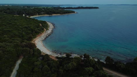 Cinematic-aerial-view-drone-above-a-seaside-rock-beach-bay-in-the-idyllic-Adriatic-mediterranean-sea-ocean-in-summer-by-the-Croatian-vacation-coast-with-blue-water-and-hidden-secret-beaches-for-travel