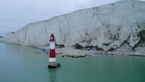 A-circling-aerial-shot-around-Beachy-Head-lighthouse-in-East-Sussex-with-the-tall-white-chalk-cliffs-near-Eastbourne