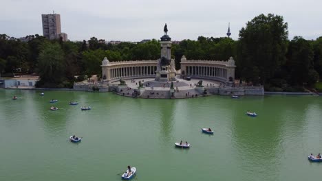 Retiro-Park---Tourists-Rowing-Boats-In-The-Lake-With-Monument-To-Alfonso-XII-In-Madrid,-Spain