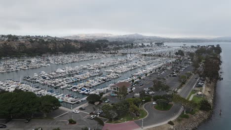 Aerial-drone-view-over-a-sailboat-and-boats,-at-a-Harbor,-in-gloomy,-overcast-California