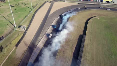 Race-Drift-Cars-With-White-Smoke-From-Burning-Tire-On-Race-Track---aerial-shot