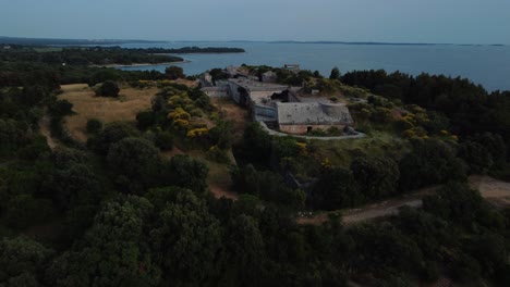 Cinematic-aerial-view-drone-above-a-historic-World-War-I-seaside-fort-fortress-fortification-by-the-idyllic-Adriatic-mediterranean-sea-ocean-with-blue-water-and-hidden-beaches-by-sunset-in-summer