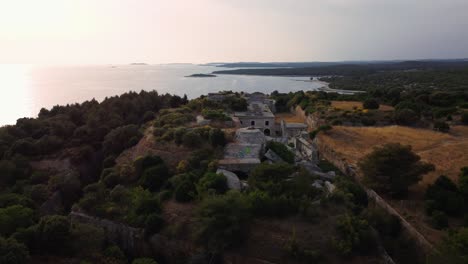 Cinematic-aerial-view-drone-sunset-circle-above-a-historic-World-War-I-fortification-seaside-fort-fortress-by-the-idyllic-Adriatic-mediterranean-sea-ocean-with-blue-water-and-hidden-beaches-in-summer