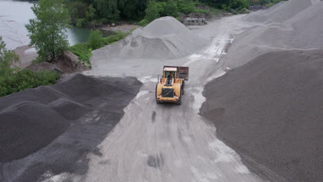 Loader-Working-And-Driving-Between-Pile-Of-Gravel-At-Gravel-Pit