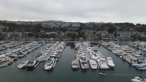 Aerial-view-of-many-of-sailboats-and-yachts,-at-the-Dana-point-Harbor,-in-California---tracking,-drone-shot