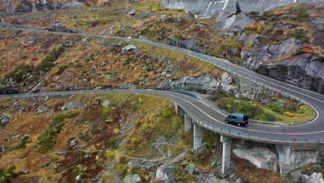 gray-camper-van-driving-Grimselpass-road-in-Switzerland-in-autumn
