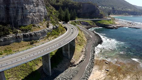 Kurvenstraße-Am-Klippenrand-Mit-Fahrzeugen-Auf-Der-Fahrt-über-Den-Grand-Pacific-Drive-An-Der-Sea-Cliff-Bridge,-NSW,-Australien