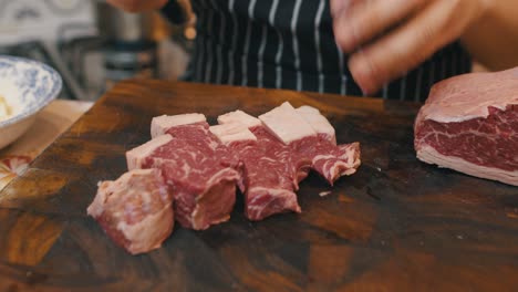 Close-up-of-cutting-meat-on-wooden-cut-board-with-kitchen-knife