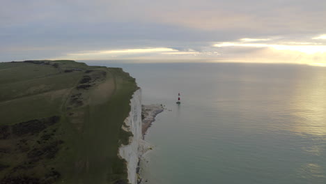 An-aerial-shot-flying-along-with-the-seven-sisters-towards-Beachy-head-lighthouse-on-the-south-coast-of-England,-with-huge-cliffs-and-sea