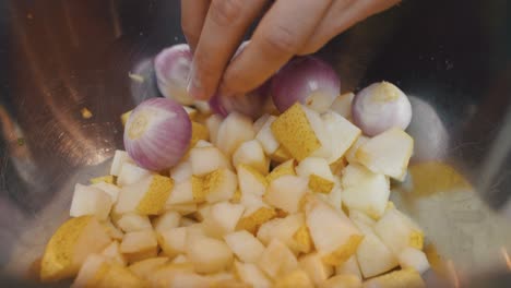 Adding-pear,-onion-and-garlic-ingredients-into-deep-metal-cooking-bowl