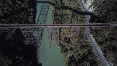 Aerial-view,-flying-over-an-abandoned-bridge-on-a-sunny-day-in-New-Zealand,-Revealing-shot