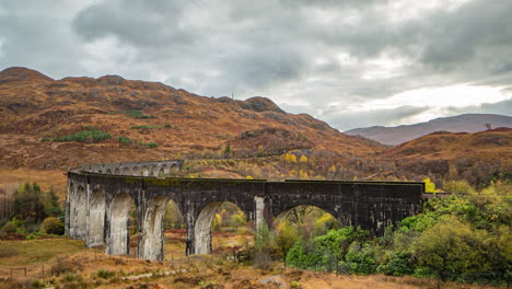 Scotland,-Scottish-Highlands-Glenfinnan-Rail-Viaduct-Time-Lapse-in-Autumn,-waiting-for-a-train-on-the-railway-with-clouds-scudding-over-landscape