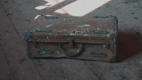 Old-broken-rusty-suitcase-on-dusty-wooden-floor