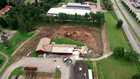 Construction-Site-With-Excavator,-Aerial-Revealing-Townscape-in-Nordic-Country