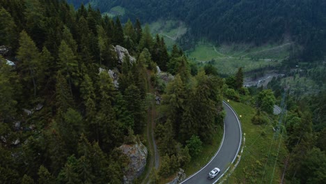 Flying-along-a-car-at-the-idyllic-mountain-serpentine-road-Plöckenpass-in-the-natural-Austrian-and-Italian-alps-in-summer-with-green-forest-trees-and-cars-on-the-street