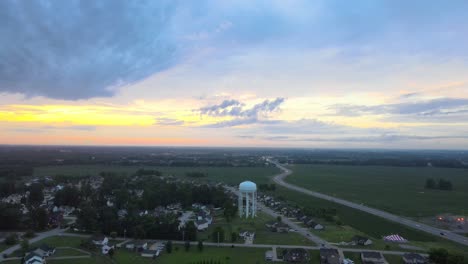 Flyaway-shot,-revealing-suburbs-and-water-tower-during-a-beautiful-sunrise