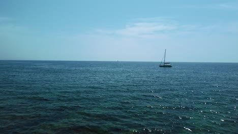 Un-Catamarán-De-Vacaciones-En-Una-Bahía-Costera-De-Aguas-Cristalinas-Azules-En-El-Idílico-Mar-Mediterráneo-Adriático-Cerca-De-La-Costa-Croata-Con-Cielo-Azul