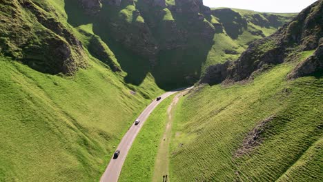 Vehicles-Driving-Through-Winnats-Pass-With-Limestone-Gorge-Covered-In-Vegetation-In-England,-UK