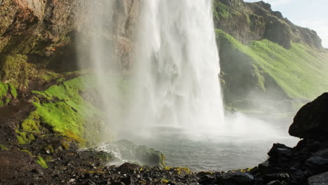 Spray-Brumoso-Sobre-Rocas-Mojadas-De-La-Cascada-Seljalandsfoss-En-Islandia