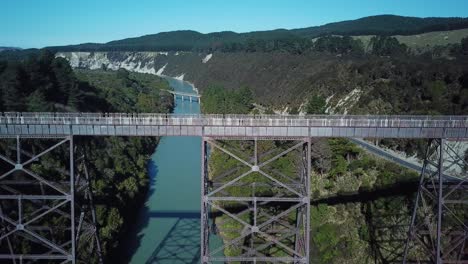Aerial-view,-close-up-of-an-abandoned-bridge-in-New-Zealand,-over-a-blue-river,-slide-left