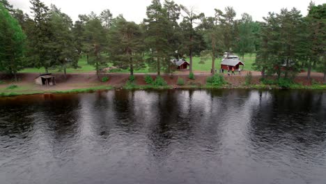 Group-Of-People-Jogging-Along-River,-Nordic-Country,-Pull-Back-Aerial