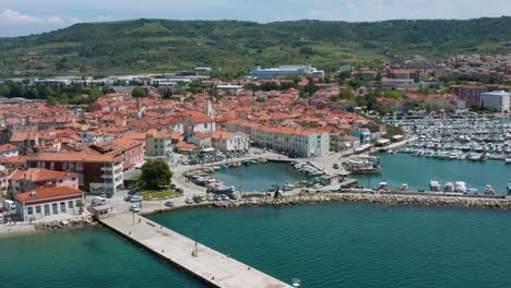 Aerial-arc-shot-focused-around-the-marina-in-Izola,-Slovenia-on-a-bright-afternoon