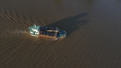 Aerial-orbiting-shot-of-industrial-cargo-ship-loaded-with-wood-cruising-on-amazon-river