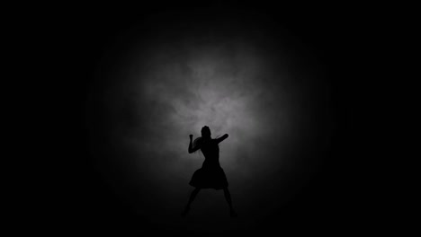 A-modern-youth-dance-performed-by-a-graceful-and-sexy-female-silhouette,-in-the-smoke-against-the-backdrop-of-spotlights