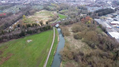 Slow-drone-flight-backwards-over-a-river-with-a-view-of-a-railroad-track