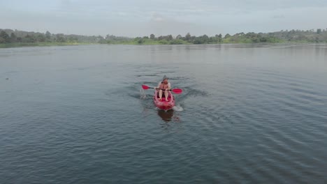 Aerial-shot-tracking-a-white-man-from-in-front-adventuring-on-a-red-kayak-paddling-on-the-river-Nile